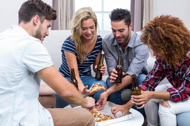 Multi amici etnici che godono di birra e pizza