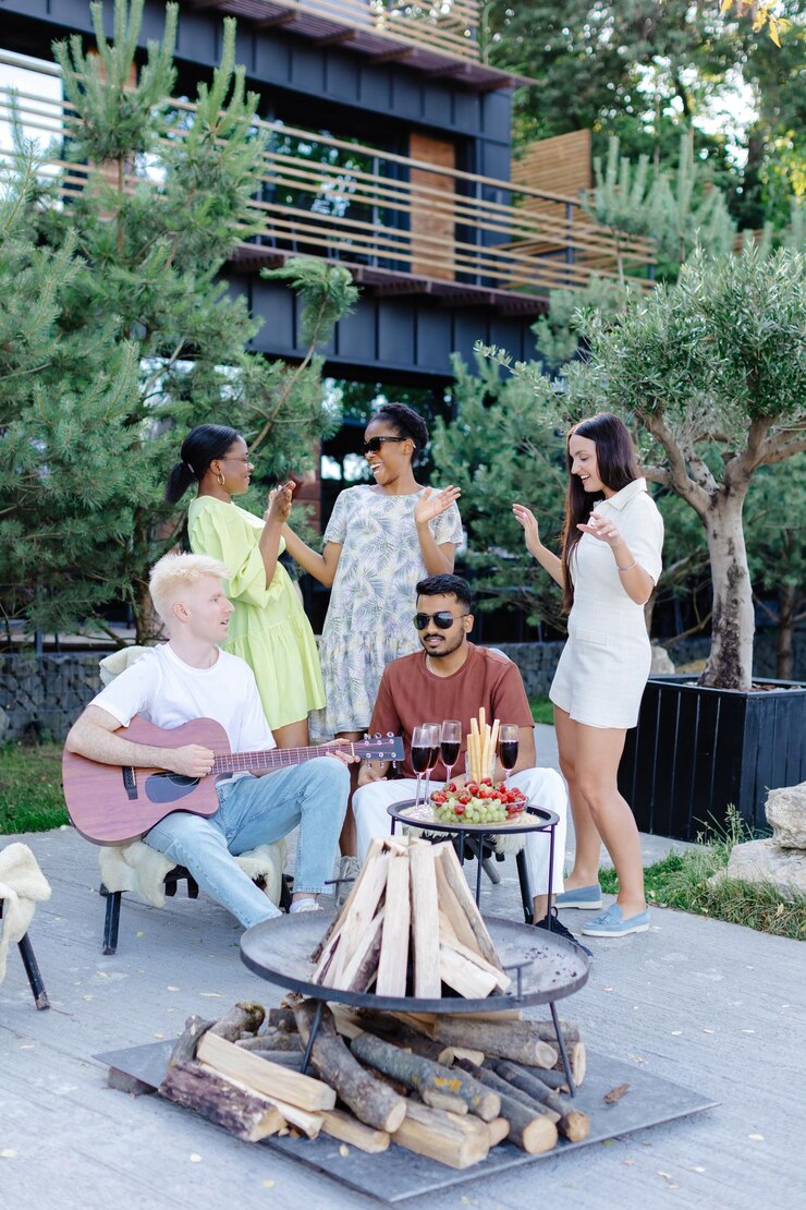 Multicultural group of people man playing guitar and friends dancing singing and having fun