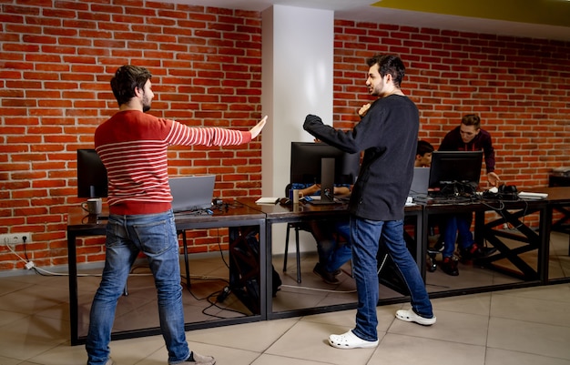 Multiethnics startup business team di sviluppatori di software che si divertono mentre fanno boxe in ufficio, emozionati diversi dipendenti che ridono godendosi attività divertenti durante la pausa di lavoro,