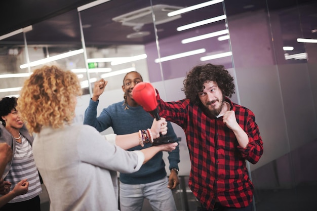 multietnica startup business team di sviluppatori di software che si divertono mentre fanno boxe in ufficio, emozionati diversi dipendenti che ridono godendosi attività divertenti durante la pausa di lavoro, lavoratori creativi amichevoli che giocano