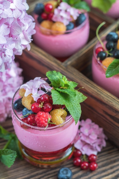 Multivitaminico estate bacca delizioso panacotta Cibo dolce con lamponi mirtilli ribes crostini e menta bouquet di ortensie rosa fondo di legno scuro
