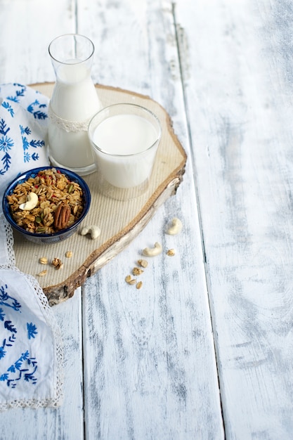 Munga in un bicchiere e in una bottiglia, muesli in una tazza blu e ananas e tovaglia con fiori blu