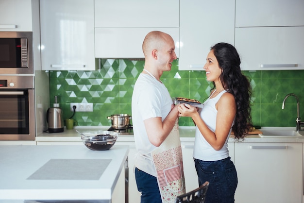 Mungitura rappresentata graficamente delle belle giovani coppie alla macchina fotografica mentre cucinando nella cucina a casa.