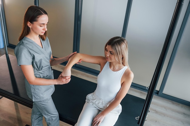 Muovere la mano La donna è in un centro sanitario che riceve aiuto dal medico