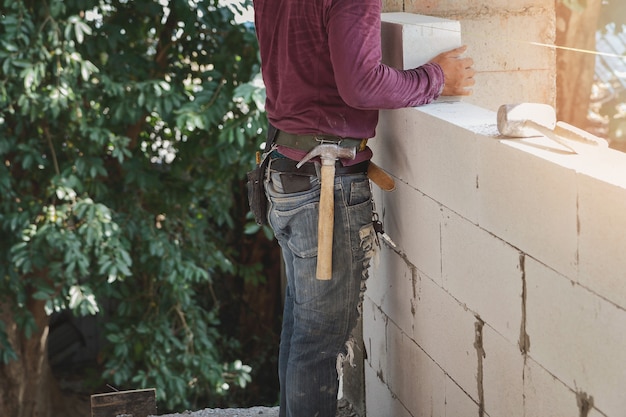 Muratore che installa i mattoni sul cantiere