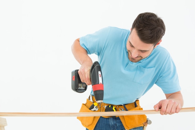 Muratore che per mezzo del trapano a mano sulla plancia di legno