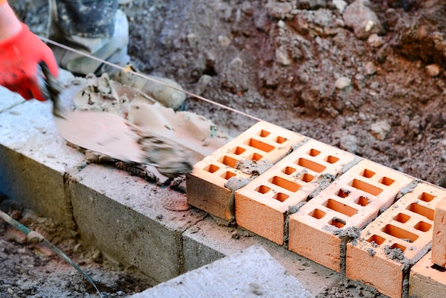 Muratore posa di mattoni in cantiere