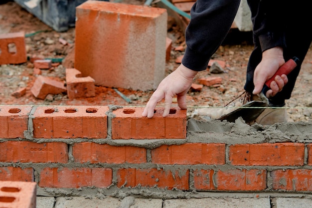 Muratore posa di mattoni su malta sul nuovo cantiere di casa residenziale