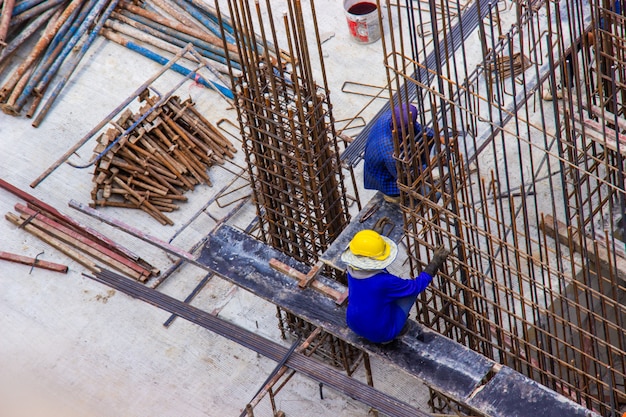 Muratori che fabbricano la barra di rinforzo della barra d&#39;acciaio grande nel cantiere di area di costruzione.