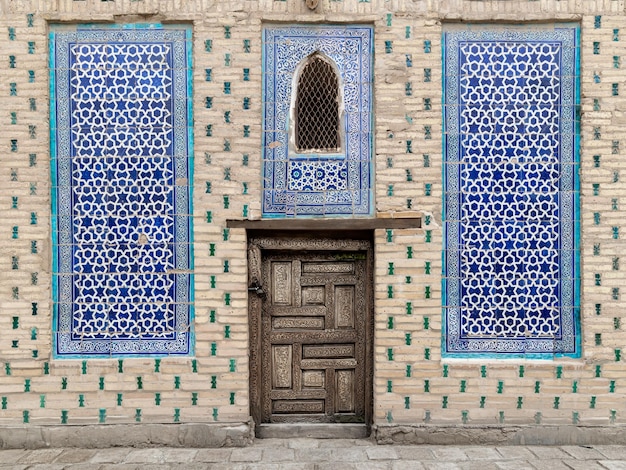 Muro del palazzo khan con porta in legno intagliato e piastrelle con intricati ornamenti Khiva Uzbekistan