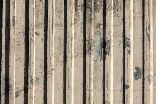 Muro di cemento grigio con linee verticali e ombra