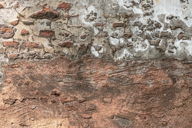 Muro di mattoni abbandonato invecchiato con intonaco distrutto