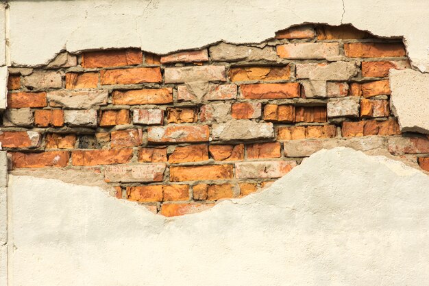 Muro di mattoni con intonaco parzialmente distrutto, sfondo o texture