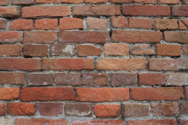 Muro di mattoni di un'antica fortezza Mattoni irregolari rossi e marroni con cemento Sfondo di mattoni