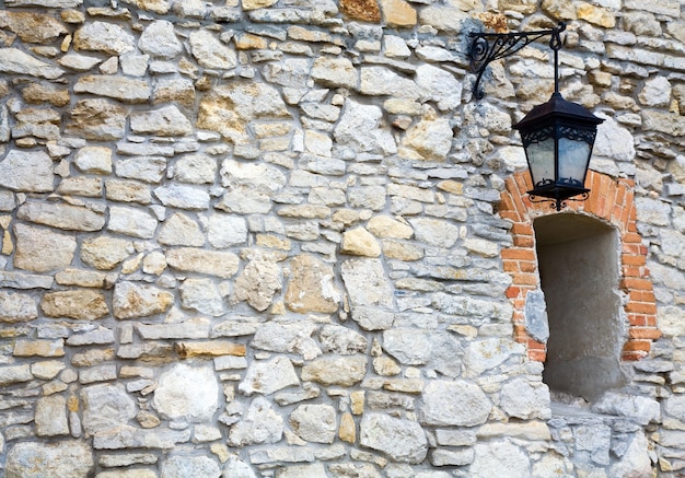 Muro di pietra con finestra e lampada