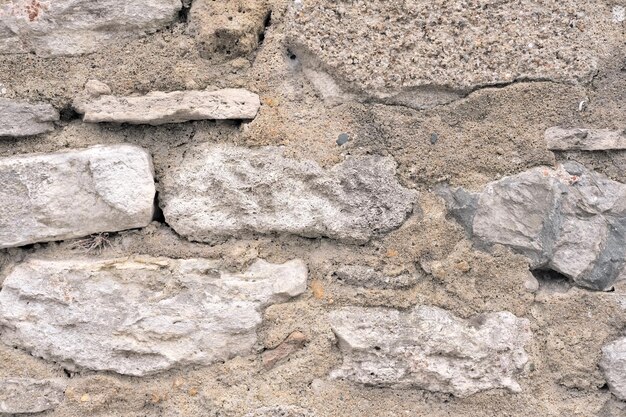 Muro di vecchio edificio fatto di pietre calcaree grezze, argilla chiara e sabbia come sfondo