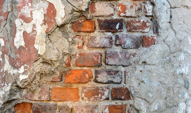 Muro rustico grezzo in mattoni d'epoca con intonaco danneggiato