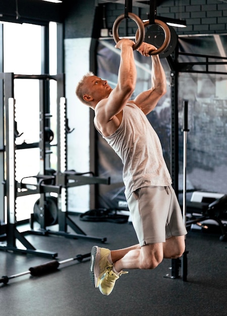 Muscleup esercizio uomo di mezza età che fa intenso allenamento crossfit in palestra su anelli di ginnastica