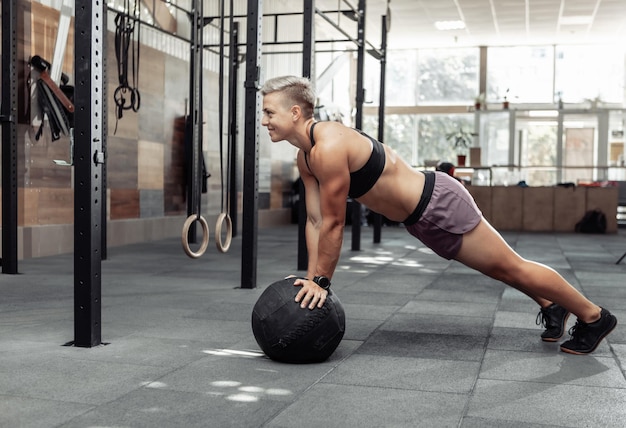 Muscolosa donna atletica push up con palle mediche in una moderna palestra. Crossfit, allenamento funzionale