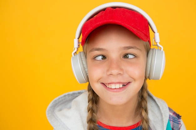 Musica con emozioni Bambino strabico su sfondo giallo Bambino divertente che ascolta la musica con le cuffie stereo Il bambino piccolo si diverte con la musica negli auricolari Musica non-stop per più divertimento