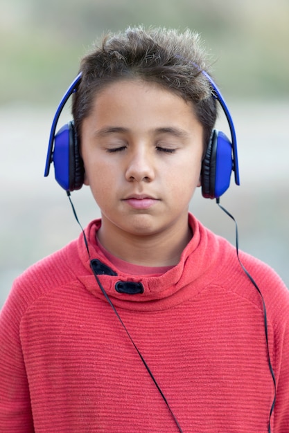 Musica d'ascolto del bambino con le cuffie e gli occhi chiusi