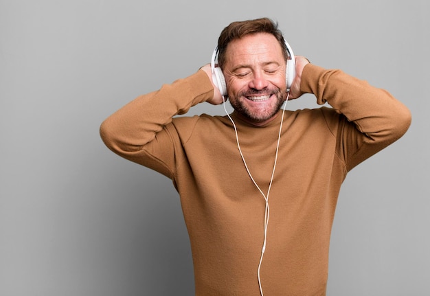 Musica d'ascolto dell'uomo di mezza età con le sue cuffie concetto di allenatore sportivo con un pallone da calcio