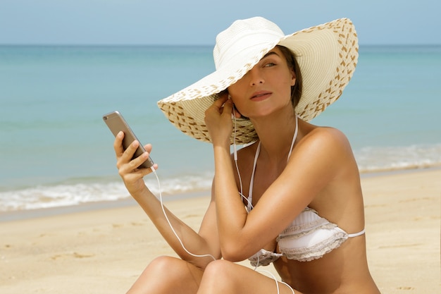 Musica d'ascolto della bella donna sulla spiaggia