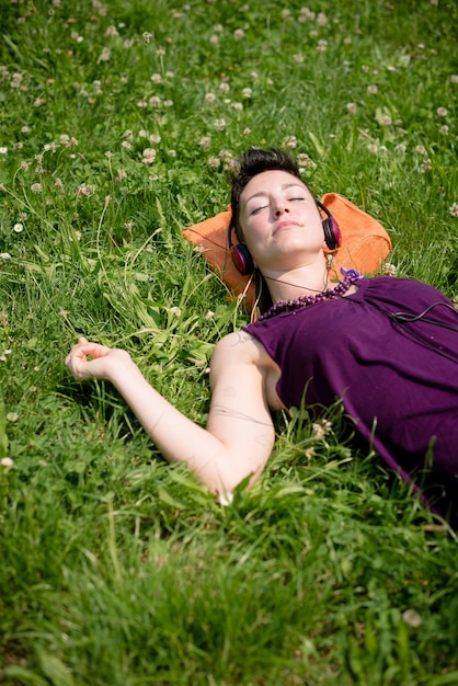 musica d&#39;ascolto della donna dei bei capelli corti dei pantaloni a vita bassa nel parco