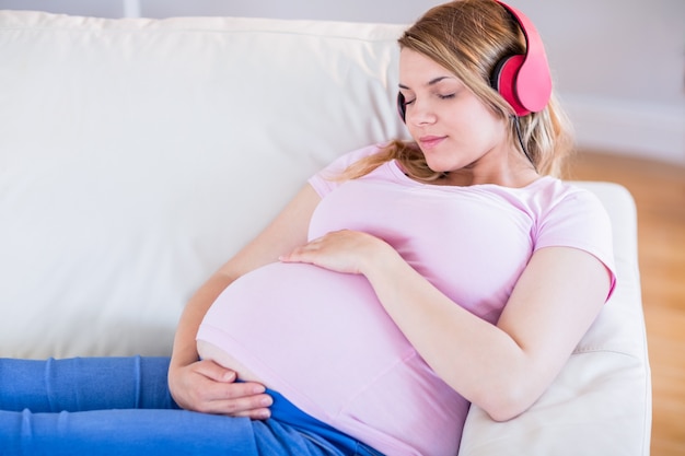 Musica d&#39;ascolto della donna incinta e toccante la sua pancia