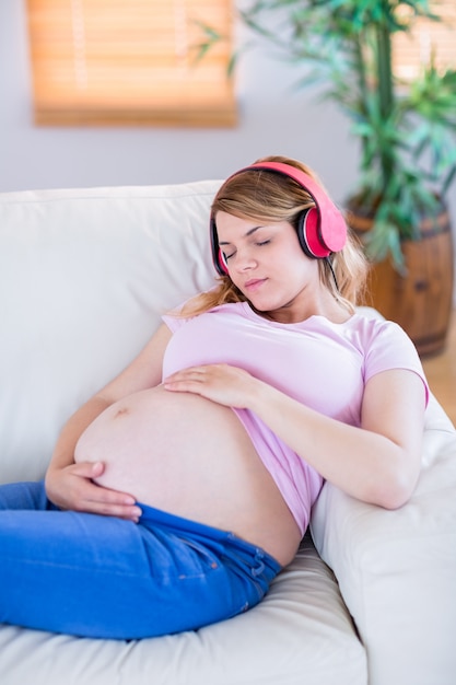 Musica d&#39;ascolto della donna incinta e toccante la sua pancia