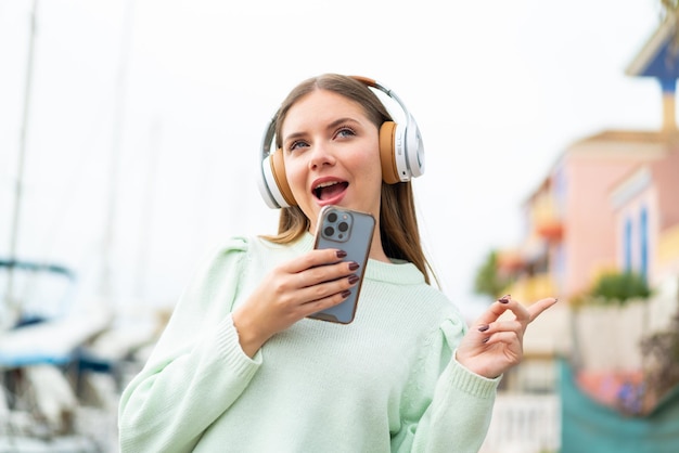 Musica d'ascolto della giovane donna abbastanza bionda con un cellulare e un canto