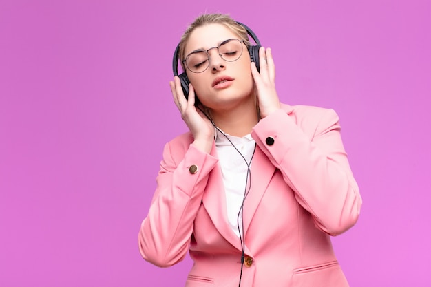 Musica d'ascolto della giovane donna bionda graziosa con le cuffie