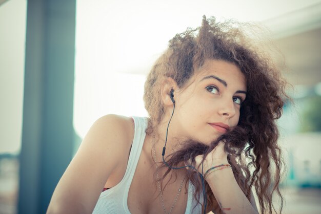 musica d&#39;ascolto della giovane donna dei bei capelli ricci lunghi dei pantaloni a vita bassa