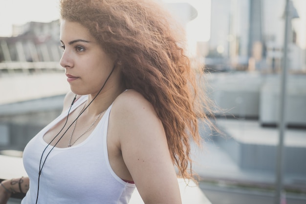 musica d&#39;ascolto della giovane donna dei bei capelli ricci lunghi dei pantaloni a vita bassa