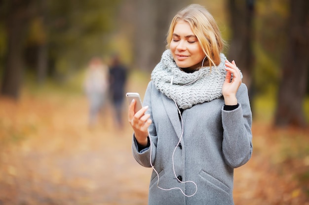 Musica d'ascolto della giovane donna di bellezza nella foresta di autunno.