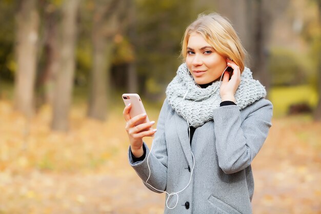 Musica d'ascolto della giovane donna di bellezza nella foresta di autunno