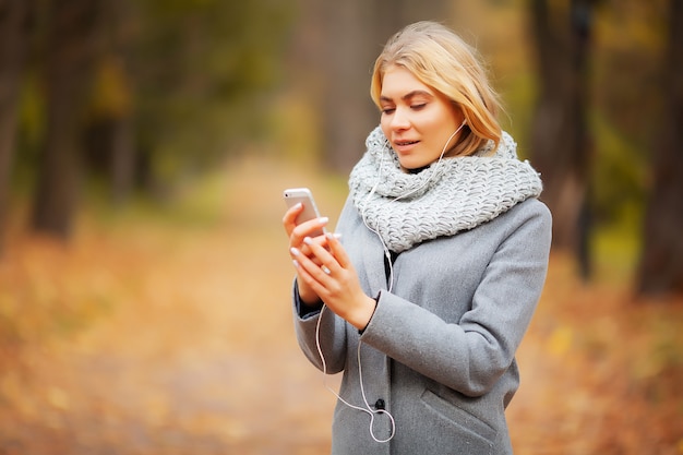 Musica d'ascolto della giovane donna di bellezza nella foresta di autunno