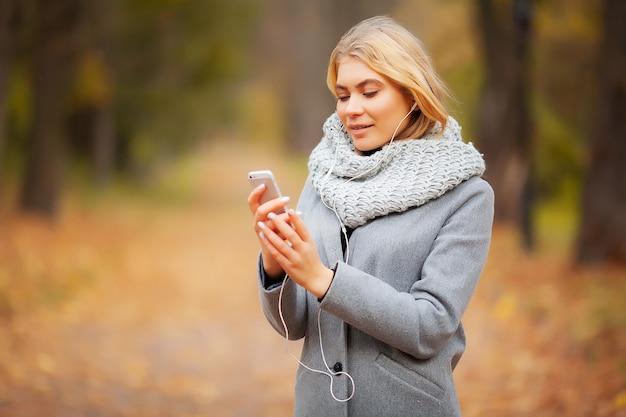 Musica d'ascolto della giovane donna di bellezza nella foresta di autunno