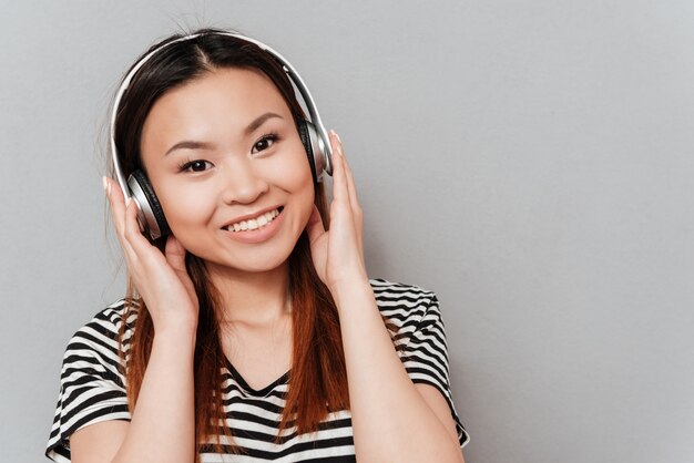 Musica d'ascolto della giovane donna graziosa felice con le cuffie