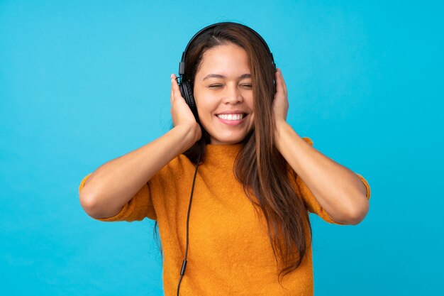 Musica d'ascolto della giovane donna sopra la parete blu