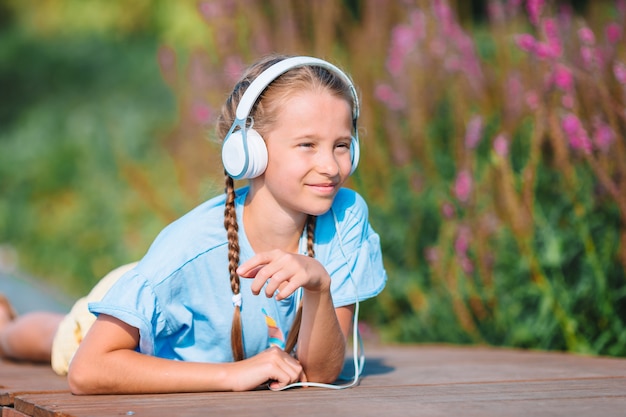 Musica d'ascolto della piccola ragazza adorabile nel parco