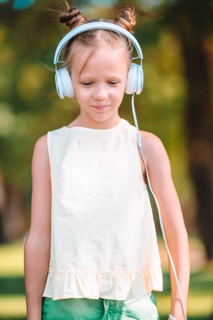 Musica d'ascolto della piccola ragazza adorabile nel parco