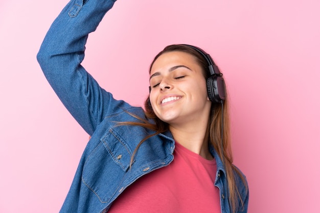 Musica d'ascolto della ragazza dell'adolescente e ballare sopra la parete rosa isolata