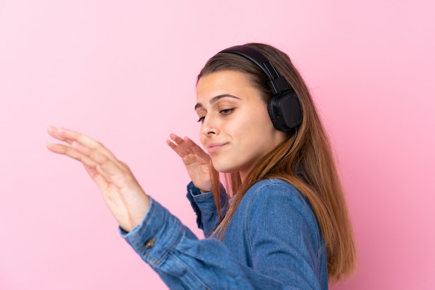 Musica d'ascolto della ragazza dell'adolescente e ballare sopra la parete rosa isolata