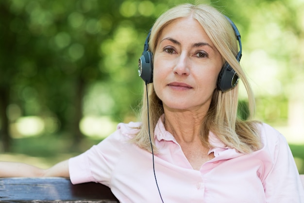 Musica d&#39;ascolto sorridente matura della donna all&#39;aperto