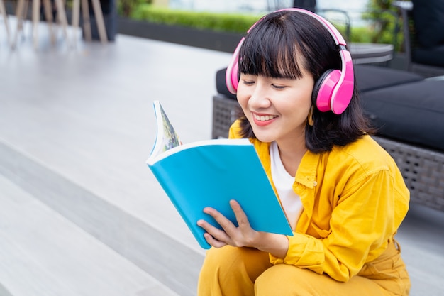 Musica di lettura e ascolto della giovane donna asiatica dalle cuffie a casa