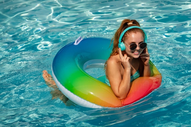 Musica estiva splendida giovane donna in posa in bikini vicino alla piscina ascolta musica vacanze estive godendosi...