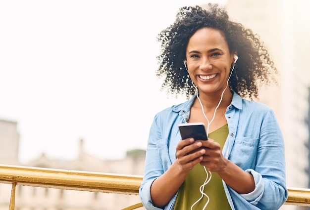 Musica felice e ritratto di donna in città con il telefono che ascolta la traccia audio e mockup nella città urbana Sorriso in viaggio e bella persona di sesso femminile africana in streaming radio per rilassarsi durante il fine settimana