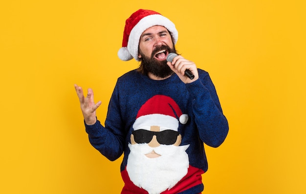 Musica natalizia. uomo maturo barbuto indossa un maglione lavorato a maglia canta nel microfono. pronto per la celebrazione. prepararsi per le vacanze invernali. divertimento di festa. Buon anno. buon Natale. saldi natalizi stagionali.