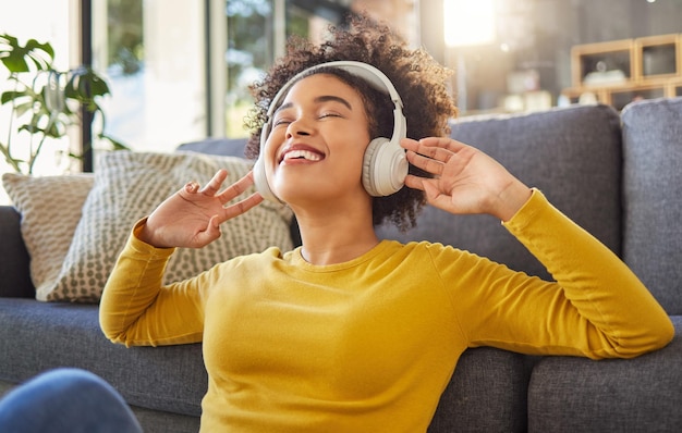 Musica per cuffie e donna felice con ballo di benessere per la salute mentale o servizio di streaming audio per giovani a casa Rilassati sul pavimento e balla di un giovane africano con elettronica o tecnologia audio